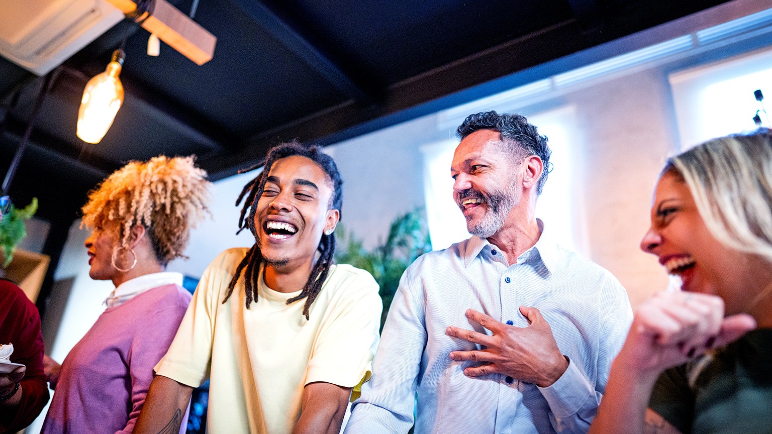 Image of a diverse group of co-workers sharing a story and laughing together.